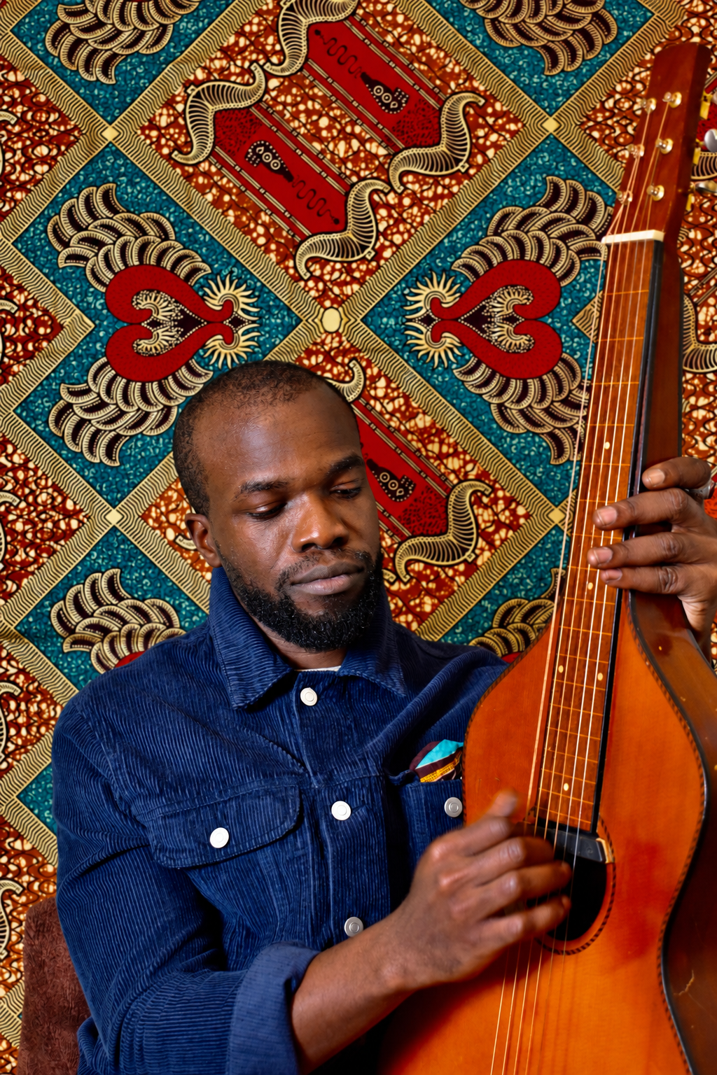 TJ holding a Weissenborn against colourful patterned fabric